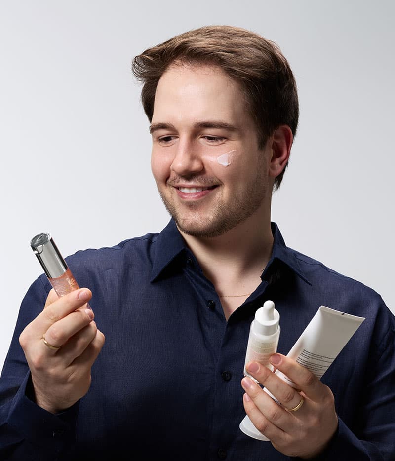 Du, criador do Beleza com Du, segurando produtos de skincare